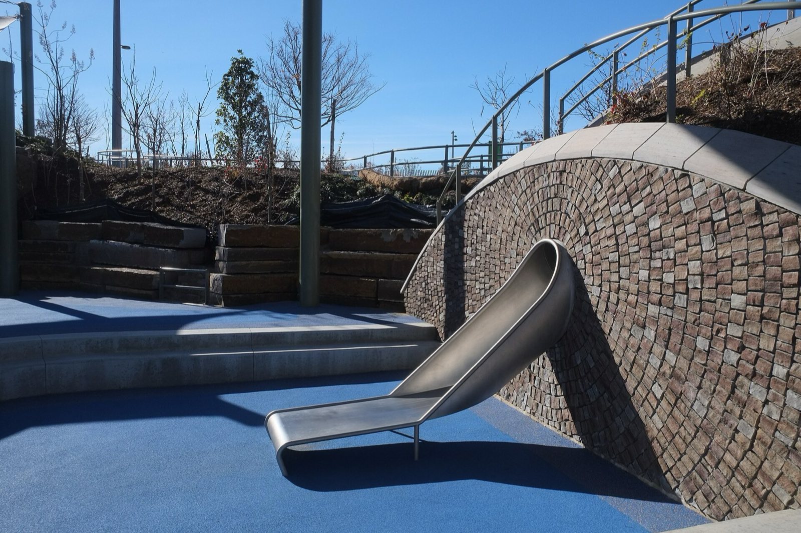 Gathering Place, single slide emerging from a stone-clad hill wall