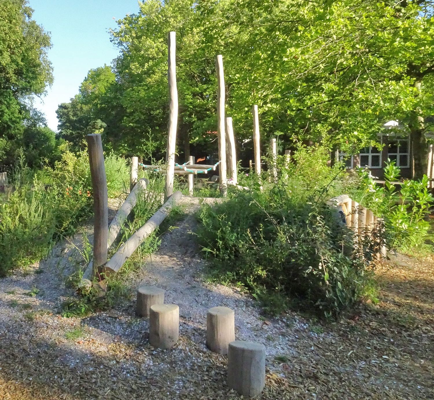 Schoolyard stump stepping stones and tall posts on gravel, Netherlands